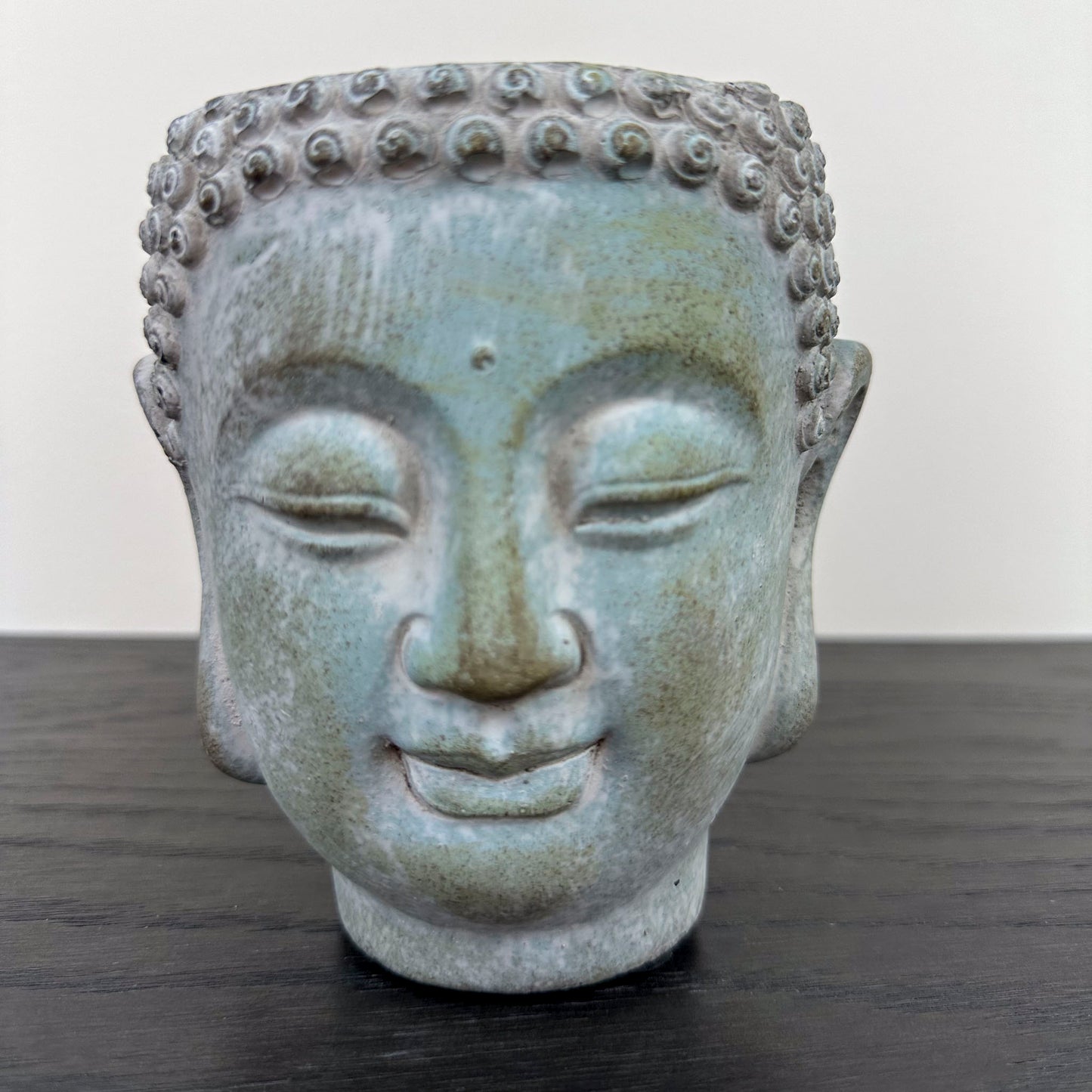 Close up of Buddha head planter, concrete finish with blue teal discoloration